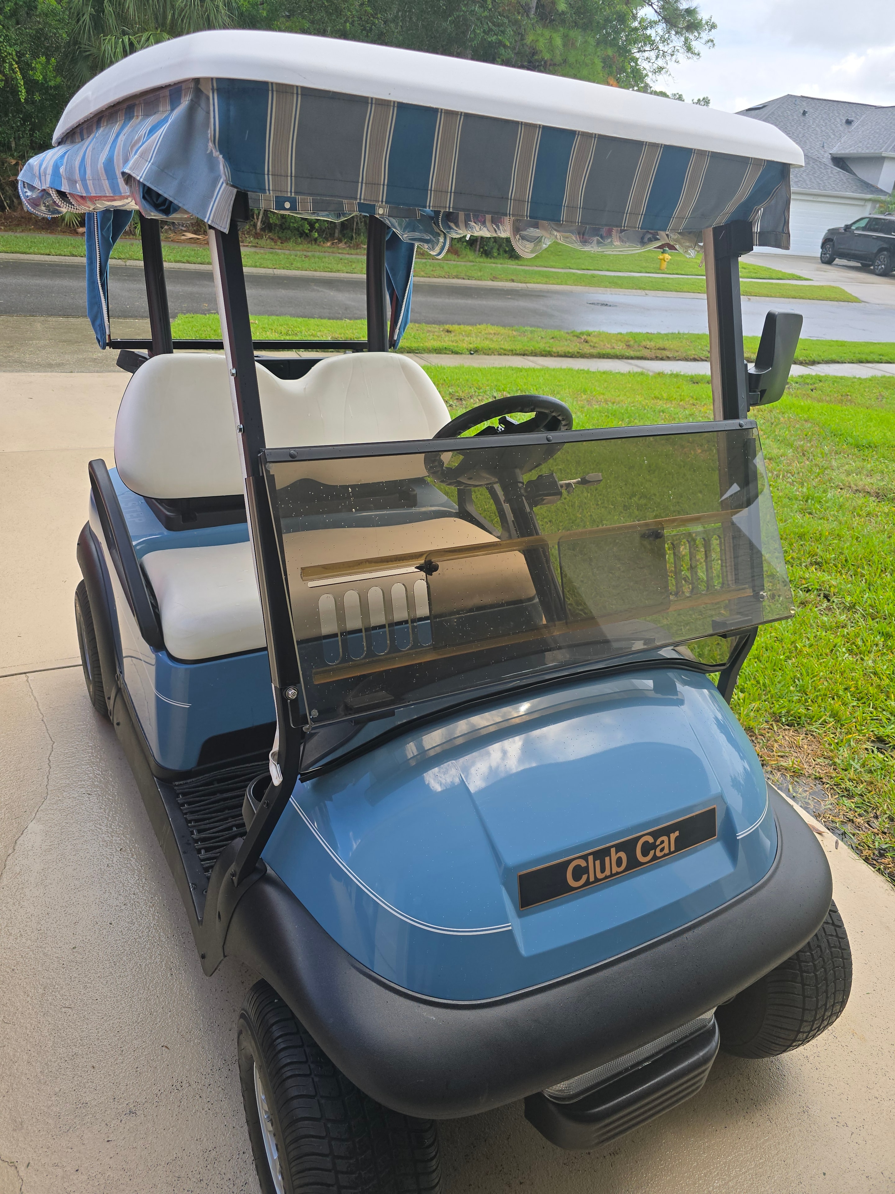 Blue Club Car golf cart with striped canopy on driveway