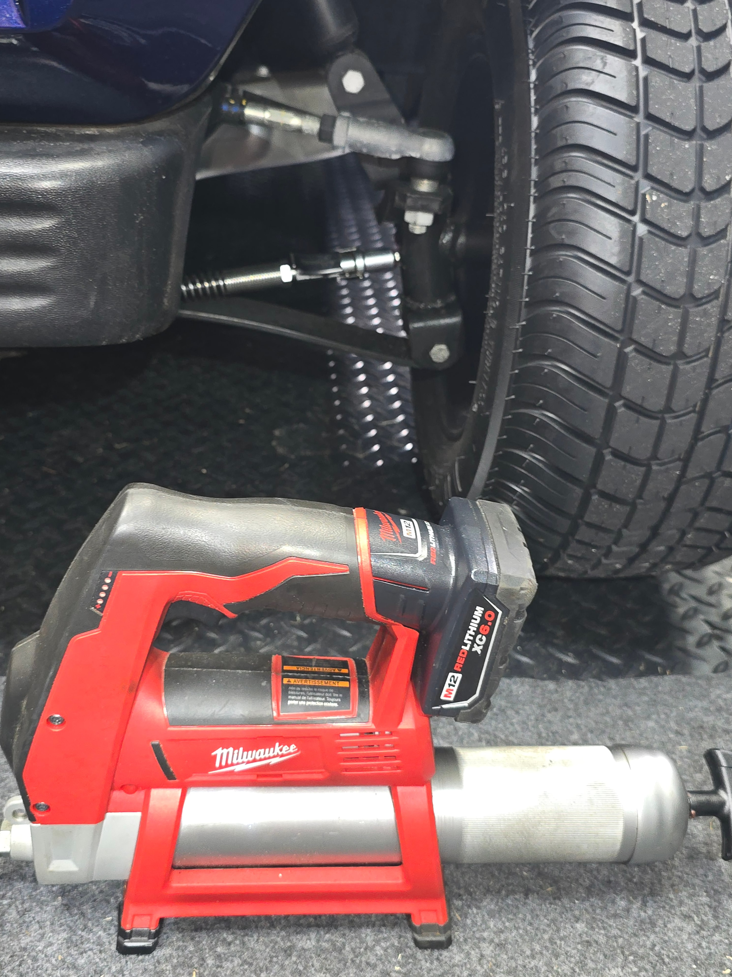 Milwaukee grease gun tool on golf cart suspension